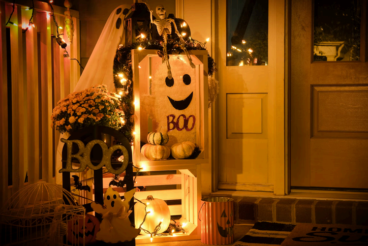 Porch decorated for Halloween with pumpkins and a BOO sign