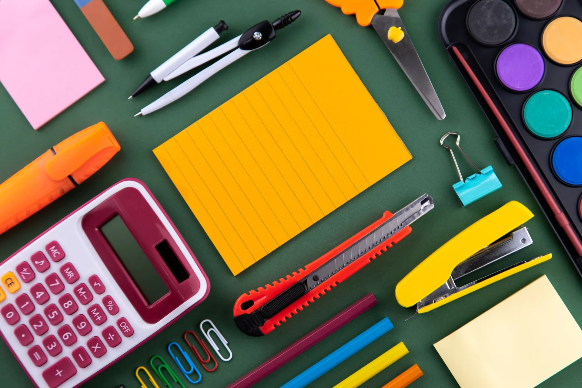 Colorful back to school supplies on a green background